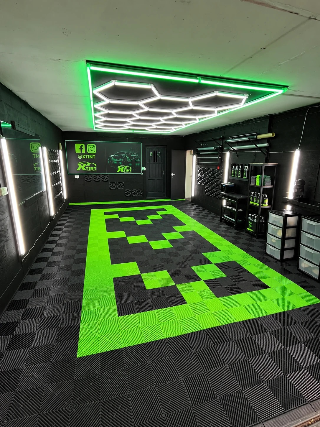Inside the XTINT studio in Nottingham — hexagonal LED ceiling lighting, green neon trim, checkered floor and the branded XTINT wall